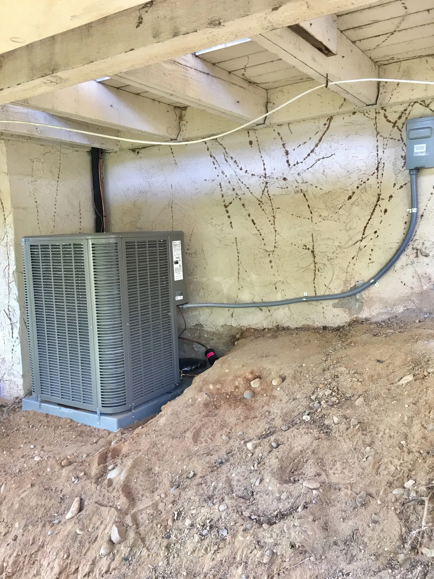 AC condenser on a new pad under a hillside deck