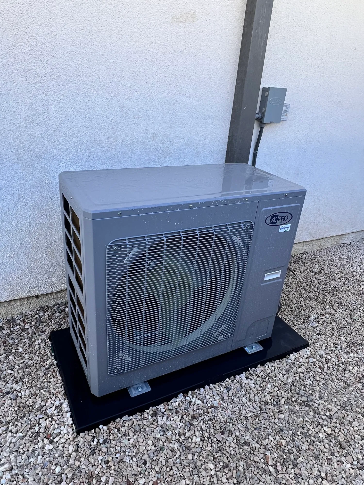 Ductless mini-split condenser on a new pad beside a stucco wall